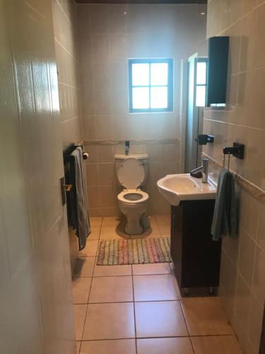 La salle de bains est pourvue de toilettes, d'un lavabo et d'une fenêtre. dans l'établissement Sibiya Guest House, à Sodwana Bay