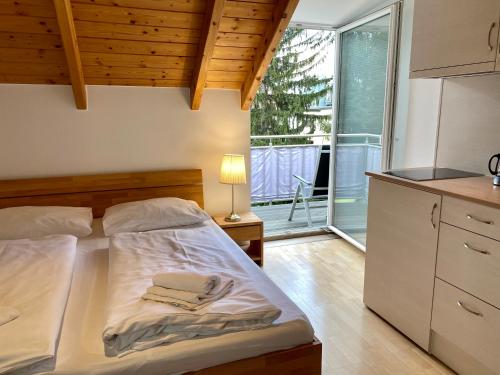 a bedroom with a bed and a kitchen with a window at AJO Vienna Balcony - Contactless Check-in in Vienna