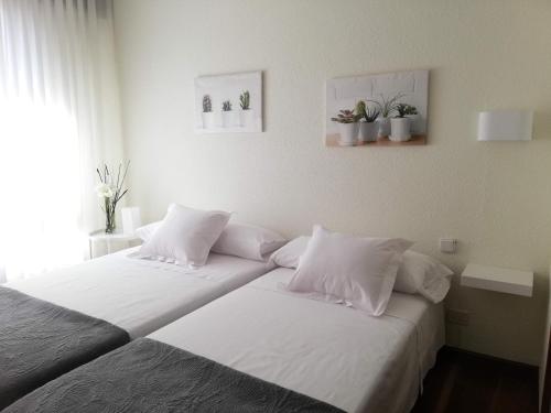 2 camas con almohadas blancas en un dormitorio en Apartamento Tellería con parking gratis, en Barakaldo