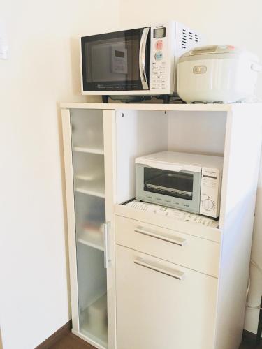 北上市にあるゲストハウス蘖 -ひこばえの白いキャビネット(電子レンジ、冷蔵庫付)
