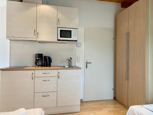eine Küche mit weißen Schränken und einer Mikrowelle in der Unterkunft AJO Vienna Balcony - Contactless Check-in in Wien