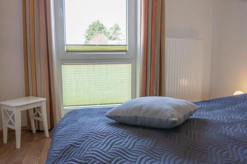 a bedroom with a bed with a pillow and a window at Haus Meeresglück Seemuschel (links) in Dahme