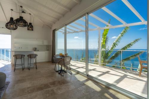 an open kitchen and living room with large windows at Escarpa - The Madeira Hideaway in Ponta do Sol