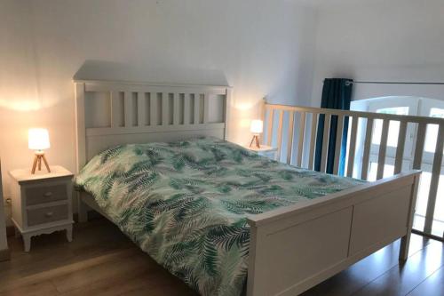een slaapkamer met een wit bed en een groene deken bij Au pied du phare... in Honfleur