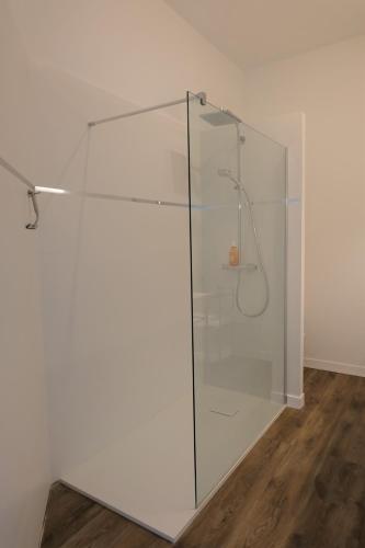 a glass shower in a room with a wooden floor at Maison d'hôtes Le 90 in Armentières