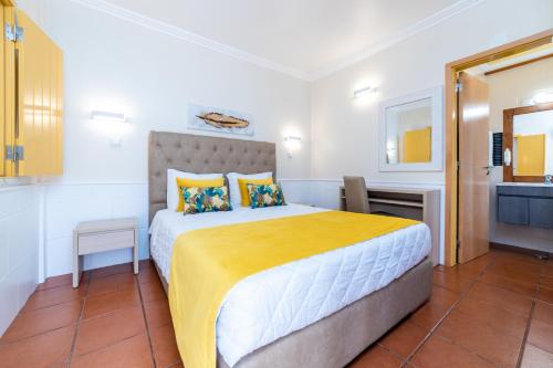 1 dormitorio con 1 cama grande con manta amarilla en Rosa dos Ventos, en Zambujeira do Mar