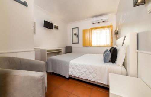 a small bedroom with a bed and a chair at Rosa dos Ventos in Zambujeira do Mar