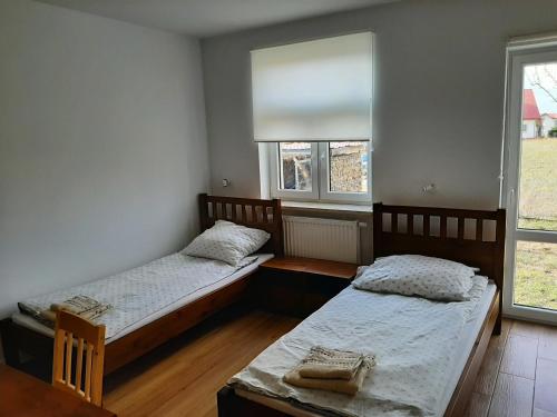 dwa łóżka w pokoju z dwoma oknami w obiekcie Dom Piotra w mieście Goniadz
