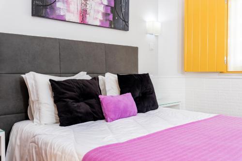 a bed with black and pink pillows on it at Rosa dos Ventos in Zambujeira do Mar