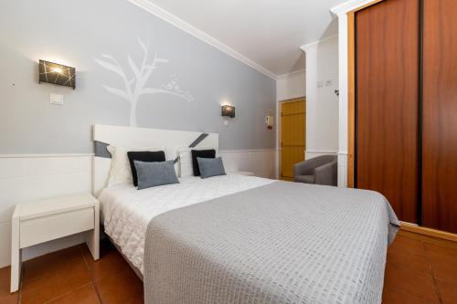 a bedroom with a white bed with blue pillows at Rosa dos Ventos in Zambujeira do Mar