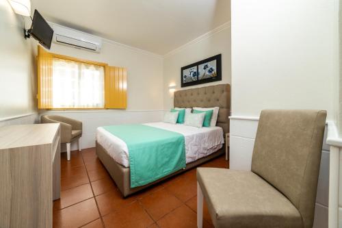 a hotel room with a bed and a chair at Rosa dos Ventos in Zambujeira do Mar