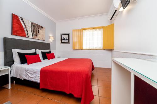 a bedroom with a bed with a red blanket at Rosa dos Ventos in Zambujeira do Mar