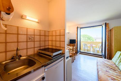 Il comprend une cuisine avec un évier et une table avec un balcon. dans l'établissement Le palais de la méditerranée, à Saint Pierre La Mer
