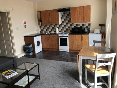 a living room with a table and a kitchen at Comfy Stays Swansea in Swansea