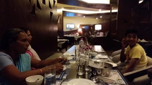 a group of people sitting at a table in a restaurant at Cocoon Luxury Business Hotel in Dhanbād