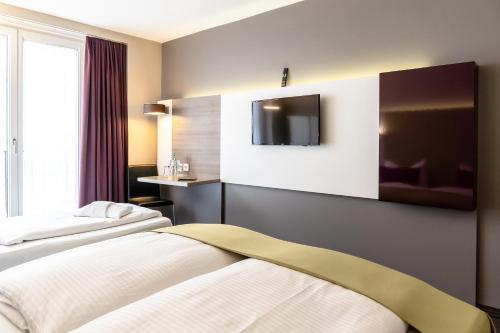a hotel room with two beds and a tv at Hotel Demas City in Munich