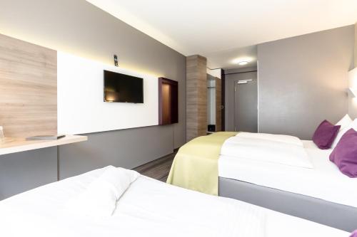a hotel room with two beds and a tv at Hotel Demas City in Munich