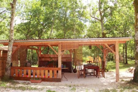 een houten paviljoen met een tafel en stoelen in een bos bij Les yourtes de Bascot in Vaylats