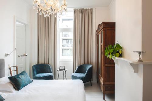 1 dormitorio con 1 cama, 2 sillas y lámpara de araña en B&B La Passion Interdite en Ostende