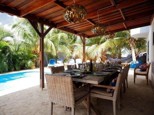 an outdoor dining area with a table and chairs and a pool at Oasis guesthouse, Boutique Style Hotel in Kralendijk