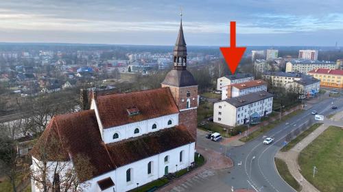 a tall building with a tower with a red arrow at City center Gauja apartment in Valmiera