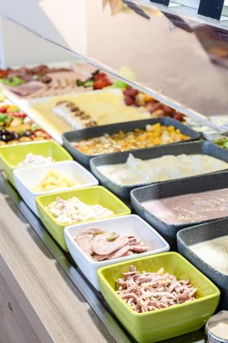 a buffet of different types of food in trays at Hotel Demas City in Munich