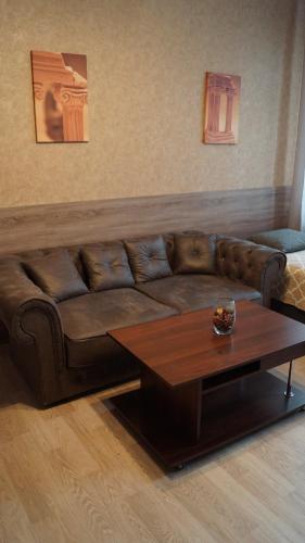 a brown couch with a coffee table in a living room at Sweet Apartments in Šiauliai