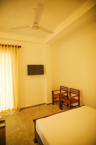 a bedroom with two beds and a table and a tv at Villa Lavish in Kandy