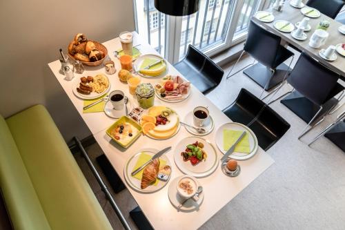 a table with breakfast food on it in a restaurant at Hotel Demas City in Munich