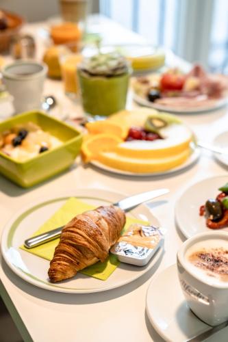 a table topped with plates of food and a croissant at Hotel Demas City in Munich