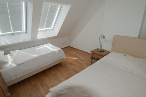 a white bedroom with two beds and a window at City Hotel Stockerau in Stockerau
