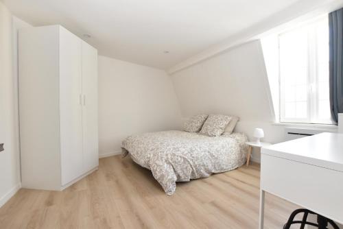 ein weißes Schlafzimmer mit einem Bett und einem Fenster in der Unterkunft Appartement Dunkerque Centre in Dunkerque