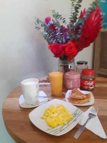 a table with plates of eggs and coffee and flowers at Hostal Brilliant in Quito