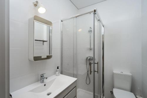 a white bathroom with a sink and a shower at Casa Mina in Faro