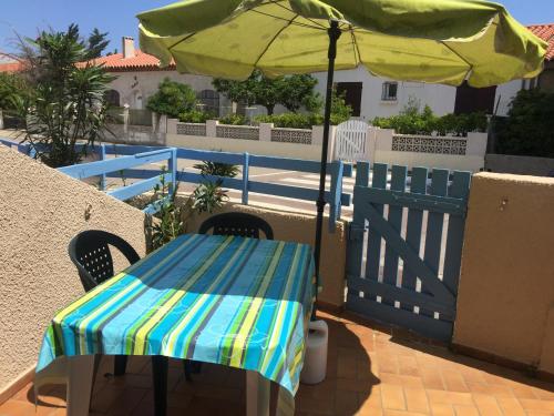 une table avec un parasol à côté d'une clôture dans l'établissement Les Mas De La Mer, à Port-la-Nouvelle