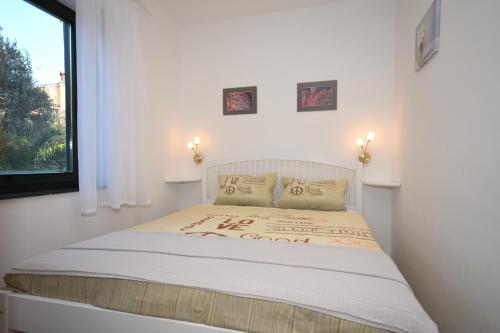 Bett in einem weißen Zimmer mit Fenster in der Unterkunft Apartment with terrace and sea view in Mali Lošinj