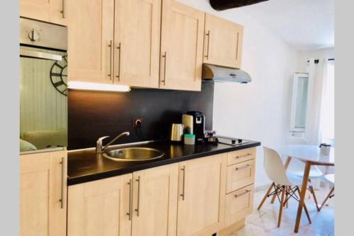 une cuisine avec des armoires en bois, un évier et une table dans l'établissement Cannes 78 rue meynadier plage, Cannes Lions Festival 3 minutes à pieds, à Cannes