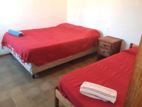 Habitación con 2 camas con sábanas rojas y mesita de noche. en las cuatro eme en Paysandú
