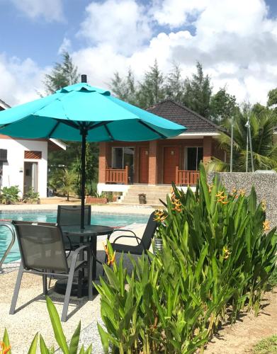 a table and chairs under an umbrella next to a pool at Casa Tanjung Jara in Dungun