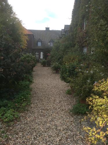 a gravel path in a garden with houses in the background at Ferienwohnung Haumannshof in Xanten