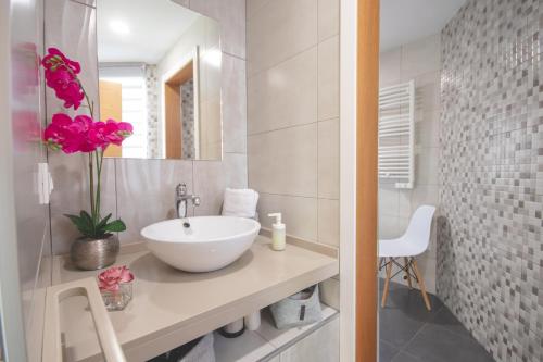 a white bathroom with a sink and a mirror at Apartamentos Coso de San Albin in Merida