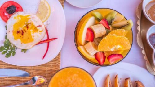 a table with a plate of fruit and a bowl of eggs at Riad Rihana Dades in Boumalne