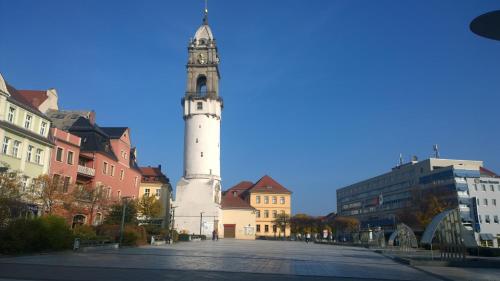 una torre di un orologio alto e bianco in una città con edifici di alte Bäckerei Bautzen - 01 #Family# a Bautzen