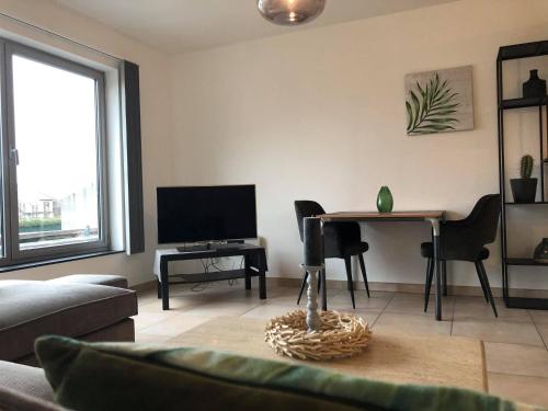 a living room with a table and a television at Apartment Fruithof Tack in Sint-Gillis-Waas