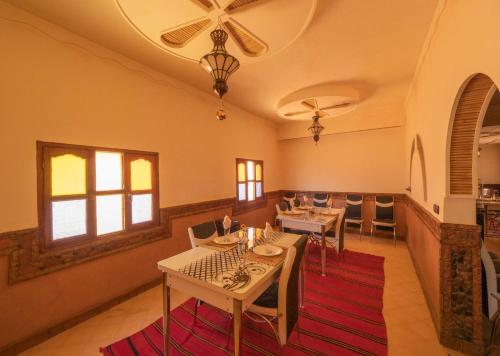 a dining room with tables and chairs on a red rug at Riad Rihana Dades in Boumalne Dades