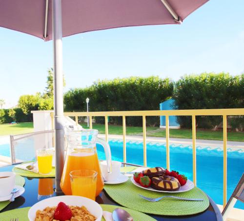 una mesa con desayuno y zumo de naranja en el balcón en Townhouse Palm Beach by Algarve Vacation, en Albufeira