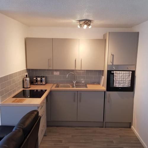 a kitchen with white cabinets and a sink at 127 - 2 Bed Deluxe Chalet, Belle Aire, Beach Road, Hemsby, Norfolk, NR29 4HZ in Hemsby