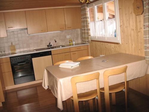 een keuken met een tafel met stoelen en een wastafel bij Chalet uf em Stutz 1 in Grindelwald