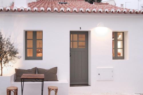 a white house with a door and a table and stools at Casa da Oliveira - Bordeira in Bordeira