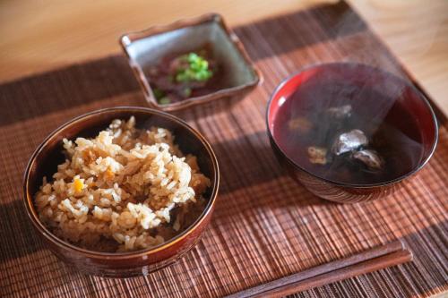 a table with a bowl of rice and a bowl of broccoli at private accommodation隠岐貸切古民家宿くすぶるハウス in Okinoshima